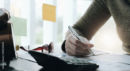 Consult financial concept. Business man pointing at papwework and using laptop computer. photo