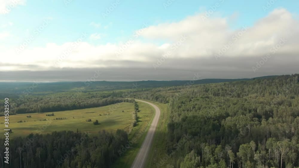 Scenic Panoramic Road View near Sunset surrouned by Forest, Nature and Mountains. Aerial Drone Shot. Northwest of Fort Nelson, Alaska Highway, Northern British Columbia. Scenic Panoramic Road View near Sunset surrouned by Forest, Nature and Mountains. Aerial Drone Shot. Northwest of Fort Nelson, Alaska Highway, Northern British Columbia.