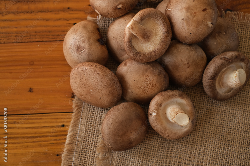 Raw Chinese mushroom or Shitake mushroom on the sackcloth over wooden table background. Selective focus. Raw Chinese mushroom or Shitake mushroom on the sackcloth over wooden table background. Selective focus.