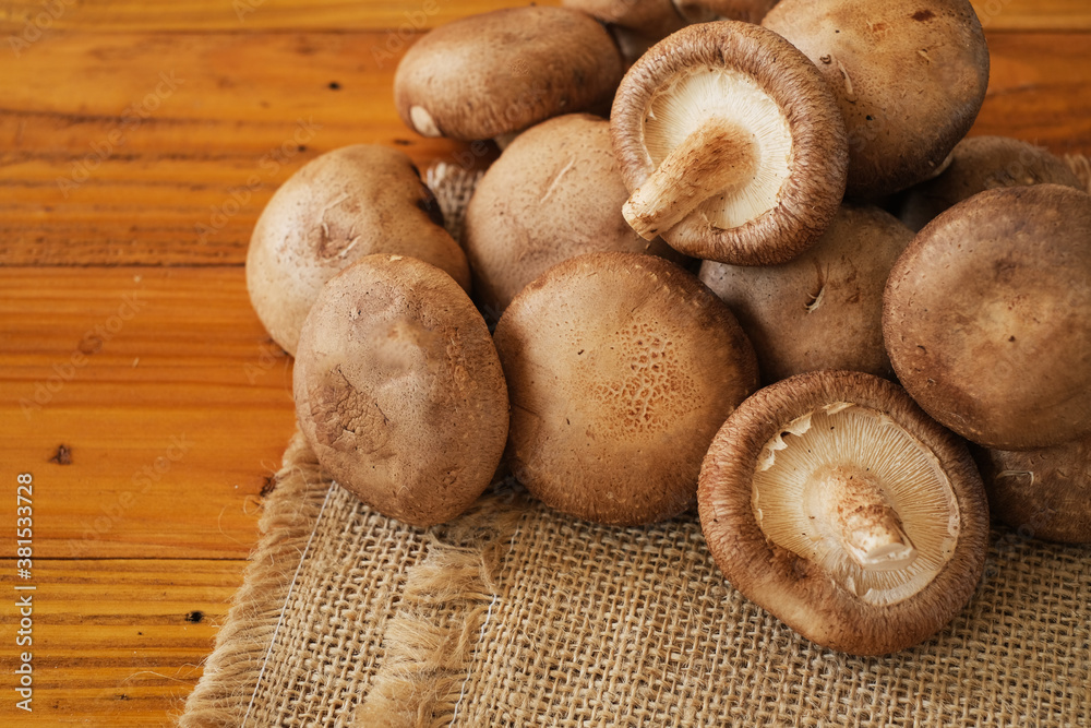 Raw Chinese mushroom or Shitake mushroom on the sackcloth over wooden table background. Selective focus. Raw Chinese mushroom or Shitake mushroom on the sackcloth over wooden table background. Selective focus.