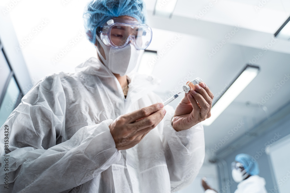 Asian young male doctor wearing white gown, holding hypodermic syringe Asian young male doctor wearing white gown, holding hypodermic syringe