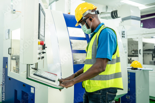 African male worker controlling the machine in industrial factory.