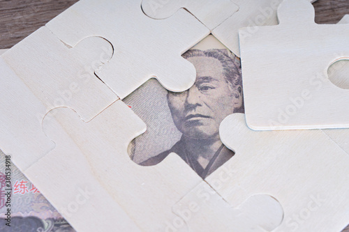 Japanese yen bill exposed from jigsaw puzzle on table