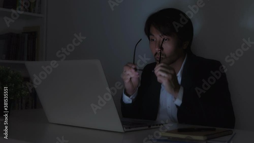Asian Insurance Agent Businessman in Suit Hold Glasses Typing Laptop and Working Late at Office in Wide View