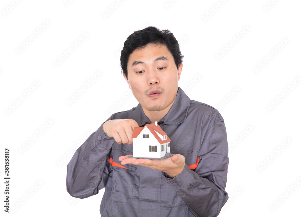 Construction worker in front of white background surprised with finger pointing at house model in other hand Construction worker in front of white background surprised with finger pointing at house model in other hand