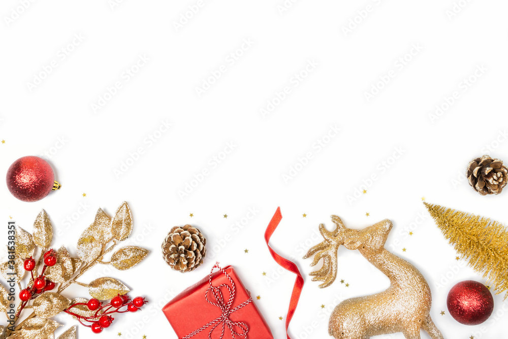Christmas background - gift box, mistletoe, fircones,reindeer and christmas balls in golden and red colors over white background. Copy space, flat lay.