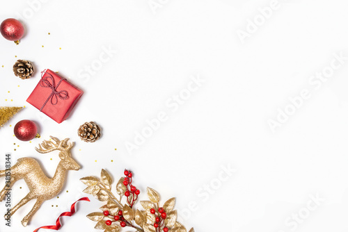 Obraz na płótnie Christmas background - gift box, mistletoe, fircones,reindeer and christmas balls in golden and red colors over white background. Copy space, flat lay. w salonie