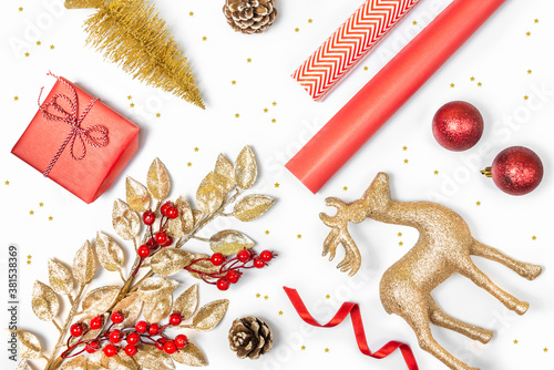 Obraz na płótnie Christmas presents preparation - gift box, mistletoe, fircones,reindeer, christmas balls and paper in golden and red colors over white background. w salonie