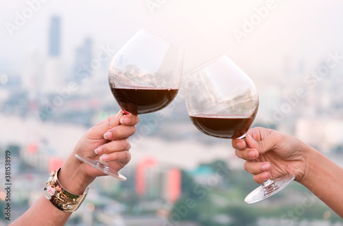 Hand of a lover's dinner is celebrated with red wine at a restaurant in a romantic atmosphere. Sunset and modern city background