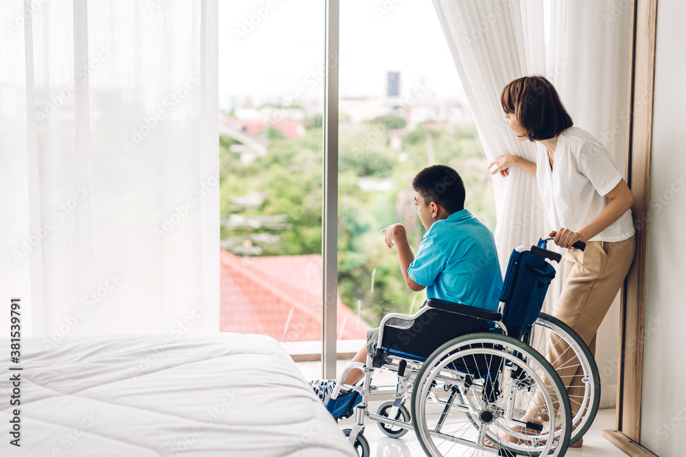 Portrait of enjoy happy love family asian mother playing and carer helping look at disabled son child sitting in wheelchair moments good time at home.disability care concept Portrait of enjoy happy love family asian mother playing and carer helping look at disabled son child sitting in wheelchair moments good time at home.disability care concept