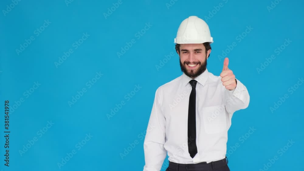 Foreman Builder on a blue isolated background. a young bearded design engineer shows a like gesture. body language .Architect gives a thumbs up - Copy space class Foreman Builder on a blue isolated background. a young bearded design engineer shows a like gesture. body language .Architect gives a thumbs up - Copy space class