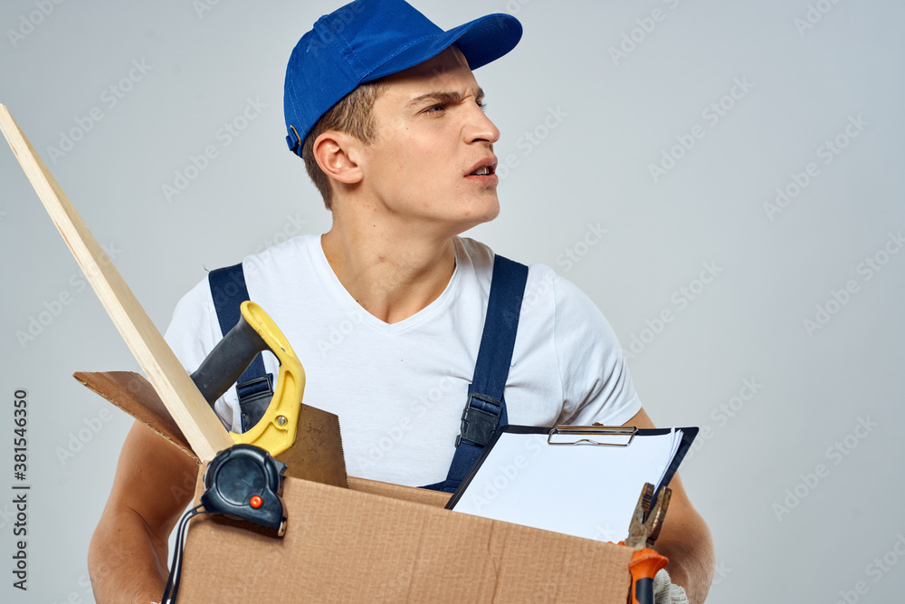 man in working uniform with a box in his hands tools loader delivery light background man in working uniform with a box in his hands tools loader delivery light background