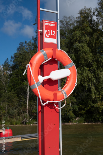 Life preserver or lifebuoy installed on a dock for emergency use in case of drowning. Lifebelt and energency phone number located at a popular beach. photo