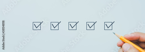 Checklist concept, Close-up, Hand holding pencil checking mark on check boxes