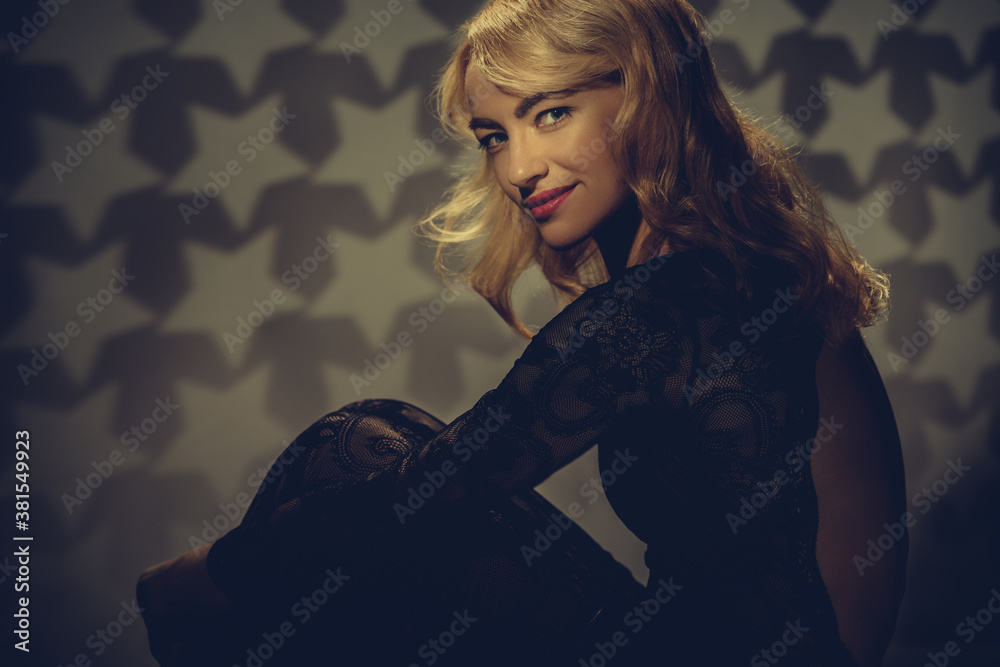 Naklejka premium Vintage portrait of pretty smiling blonde woman posing in black dress