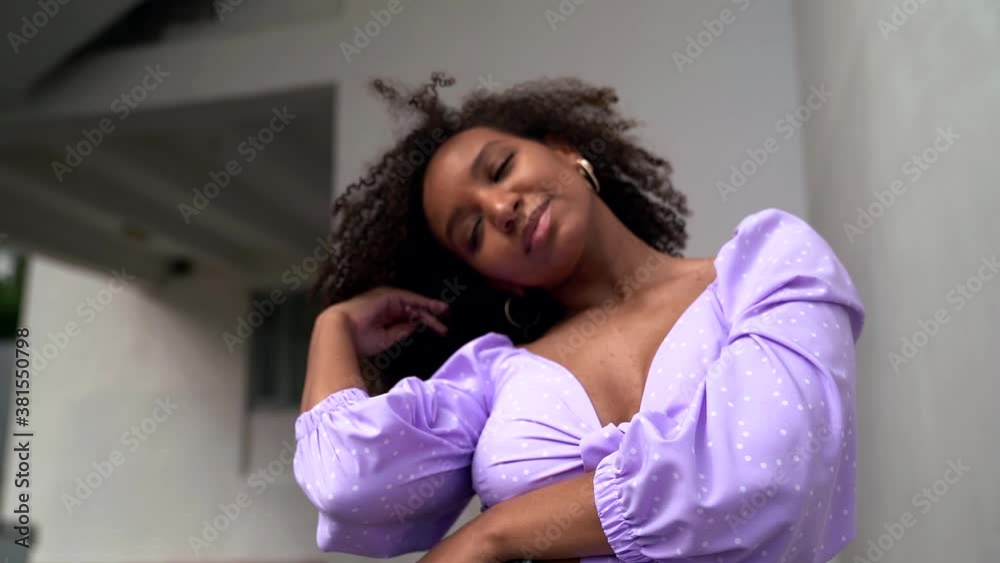 playful black woman is flirting with camera, playing with her black curly hair and looking playful black woman is flirting with camera, playing with her black curly hair and looking