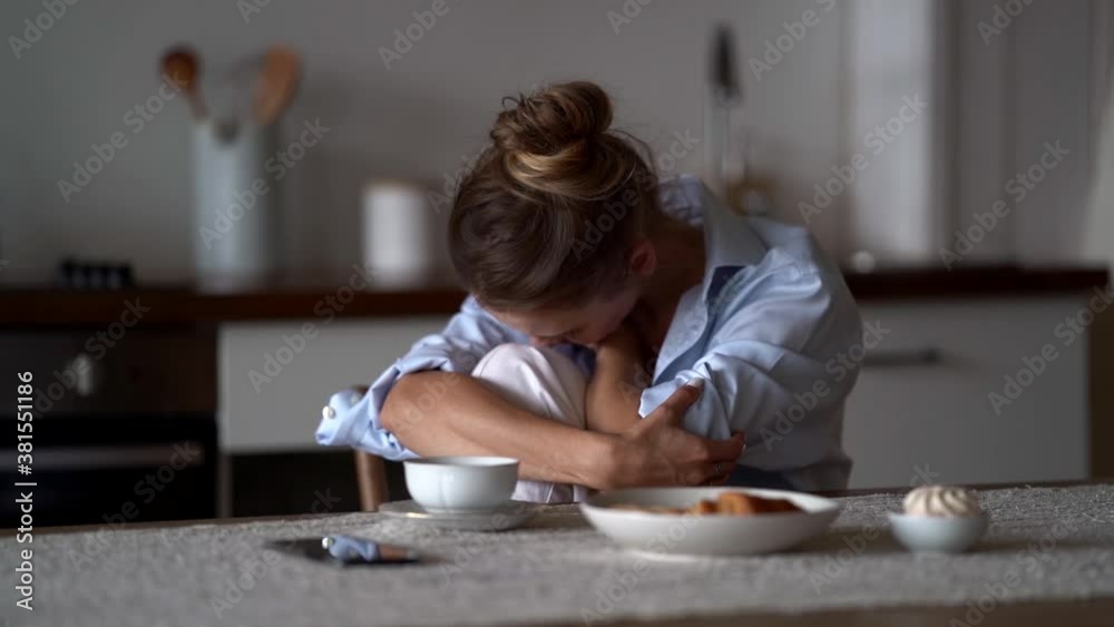 alone sad woman is suffering, sitting at kitchen of her flat alone sad woman is suffering, sitting at kitchen of her flat