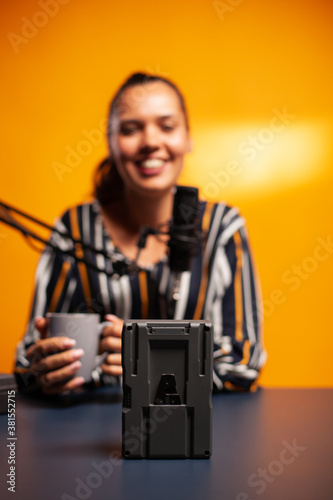 Videographer filming battery with v-lock during podcast. Professional videography gear review by content creator new media star influencer on social media. photo