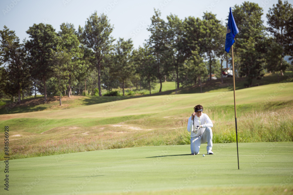 Obraz premium Golfers sit on the green to see the direction of putting golf balls