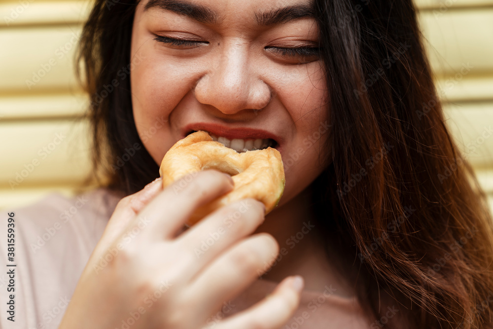 Asian chubby woman eating sweet donut.