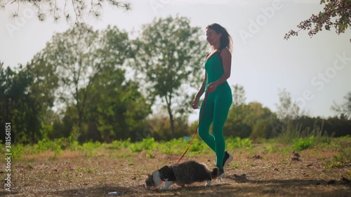 Wallpaper Mural A beautiful athletic woman in a sporty turquoise overalls walks with her fluffy cat on a leash in the forest on a green lawn. Cute kitten walks in the park with the owner. Pet care. Slow motion Torontodigital.ca