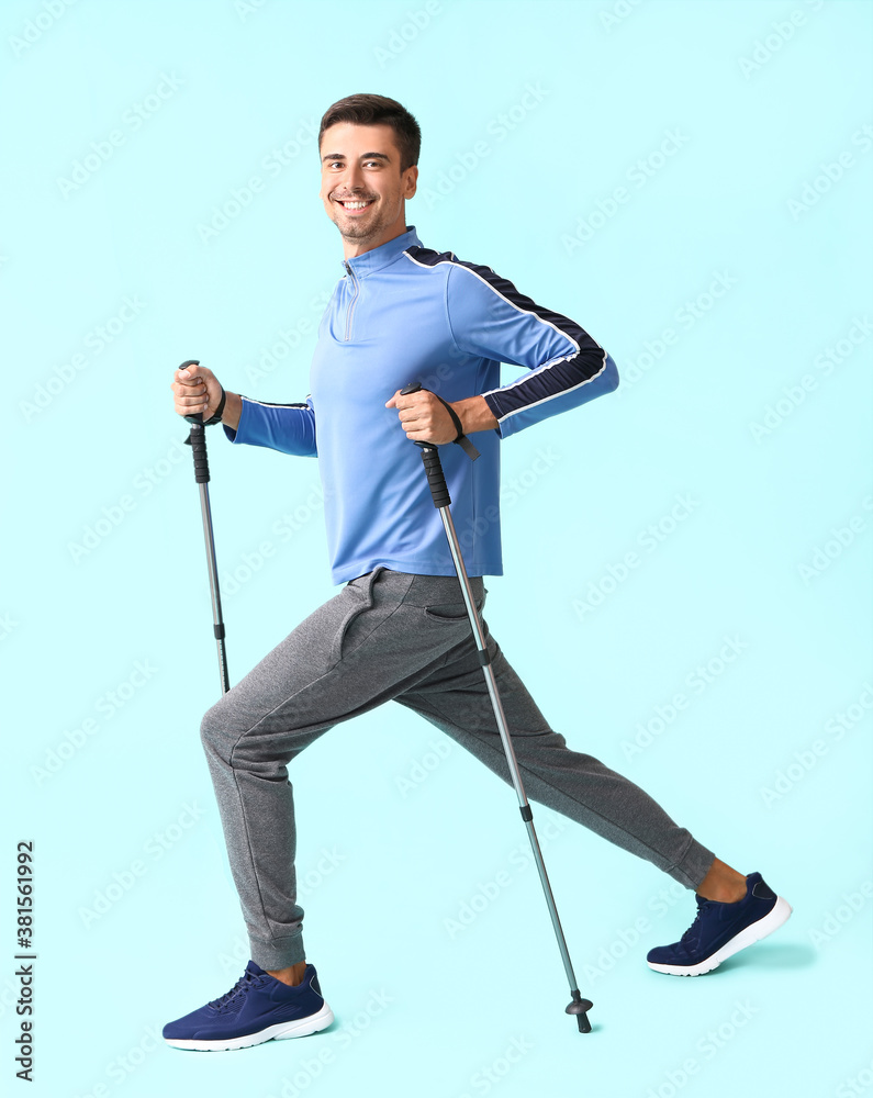 Young man with walking poles on color background Young man with walking poles on color background