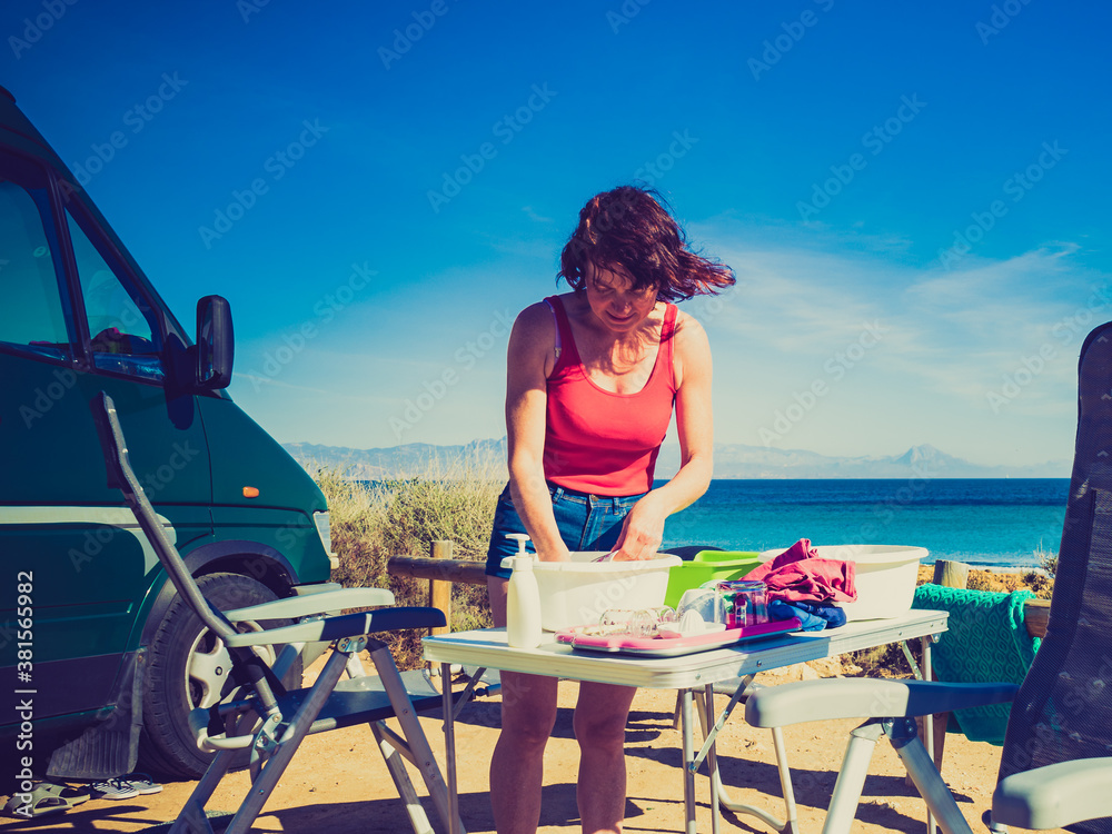 Woman wash dishes in bowl, capming outdoor