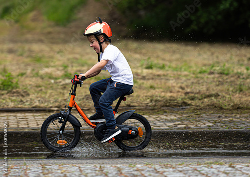 Fototapeta Naklejka Na Ścianę i Meble -  Happy boy in safety helmet riding his bike over water