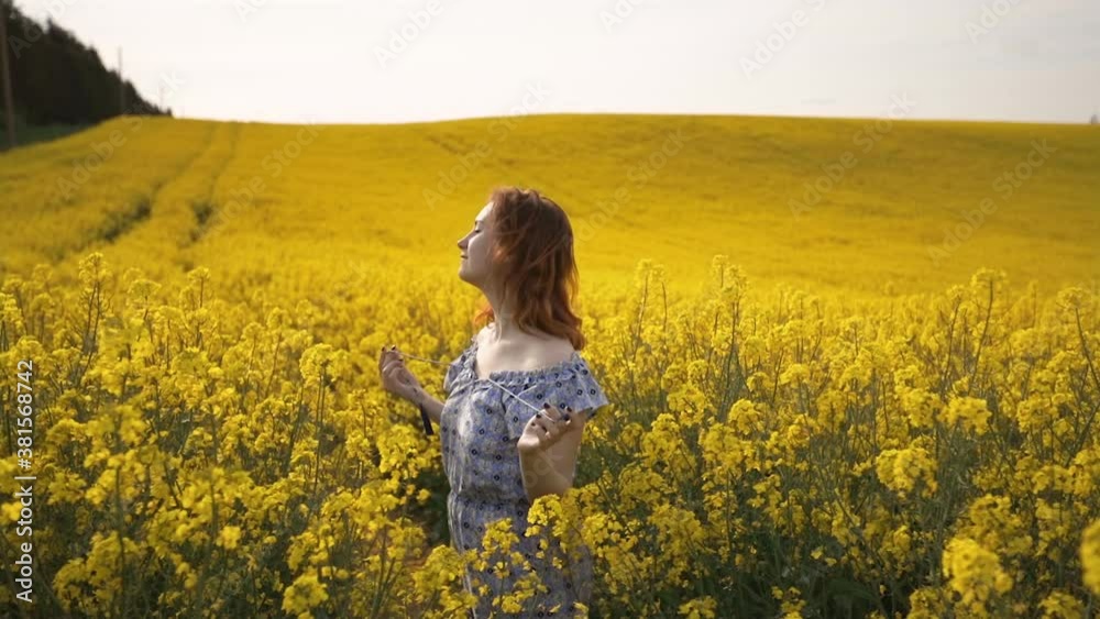 Romantic woman enjoys Spring in rapeseed field and smiles Romantic woman enjoys Spring in rapeseed field and smiles