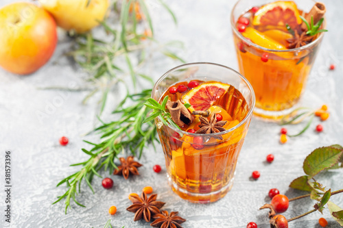 Winter or autumn hot healing tea with pear, orange, lingonberries, sea buckthorn and spices in glass cup.