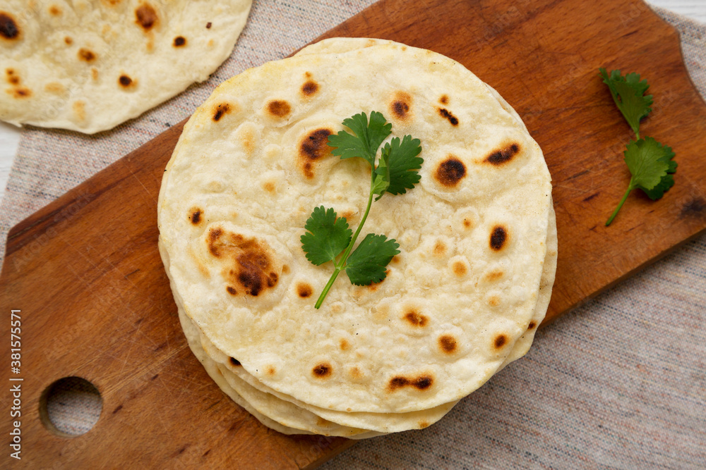 Homemade Roti Chapati Flatbread on a rustic wooden board, top view. Overhead, from above, flat lay. Close-up. Homemade Roti Chapati Flatbread on a rustic wooden board, top view. Overhead, from above, flat lay. Close-up.