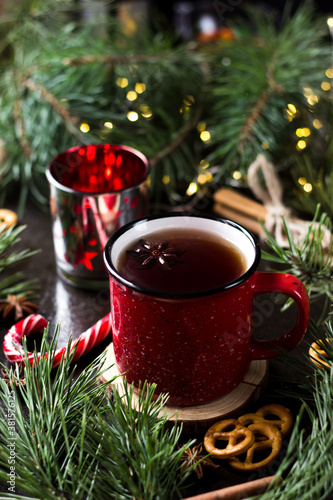 New year's tea party with spices. Red mug with tea surrounded by garlands, fir branches and spices   © SVETLANA