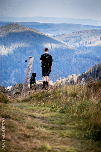 A seventeen year old boy and his dog look out over the edge of a cliff in the Black Forest of Germany. 