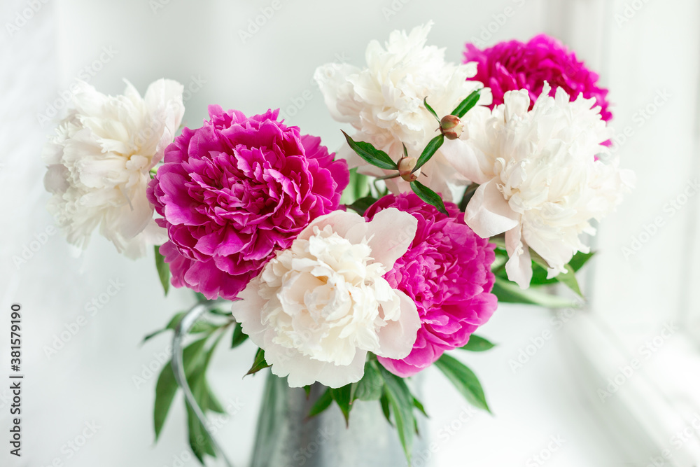 Bouquet of beautiful peonies on the windowsill. Pink and white peonies in a tin jug. Soft focus