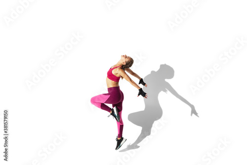 Butterfly. Beautiful young female athlete practicing on white studio background, portrait with shadows. Sportive fit model in motion and action. Body building, healthy lifestyle, style concept.