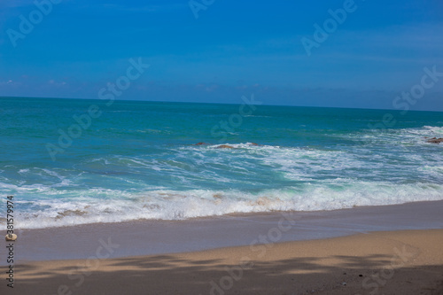 Natural background of seaside scenery (with coconut trees, boulders, sandy beach) and blurred sea waves.