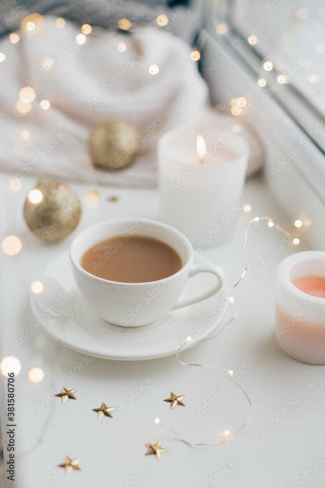 New Year and Christmas decor with a garland and a cup of coffee on the window.