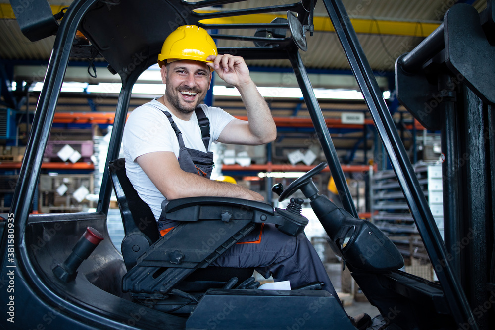 Portrait of smiling professional forklift driver in factory's warehouse. - obrazy, fototapety, plakaty 