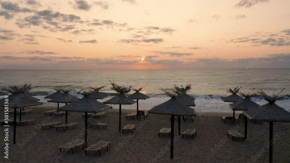 Video with straw sunshades and sunbeds on an empty sandy beach at sunrise Video with straw sunshades and sunbeds on an empty sandy beach at sunrise