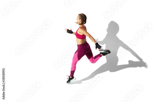 Energy. Beautiful young female athlete practicing on white studio background  portrait with shadows. Sportive fit model in motion and action. Body building  healthy lifestyle  style concept.