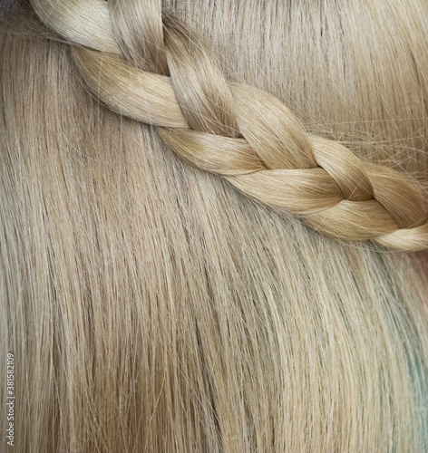 The texture of blonde women's long hair with a pigtail. Hairstyles, hair health, hair care. photo