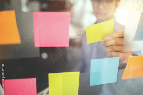 Business people brainstorming putting sticky note on glass wall, Selected focus. photo