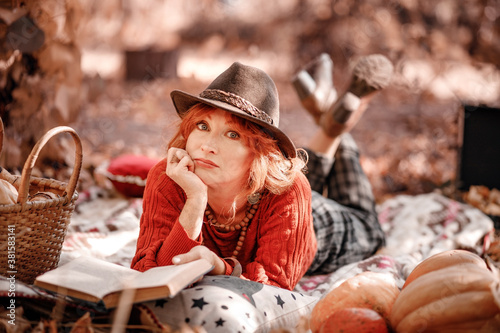 Canvastavla Autumn portrait of a red-haired woman in hat lying on a plaid in the park