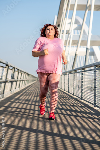 Fototapeta Naklejka Na Ścianę i Meble -  Full length of fat woman running outdoors on a beautiful sunny day.