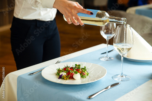 Spanish tomato salad and waiter pouring white wine