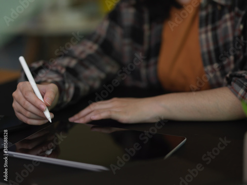 Female using digital tablet with stylus on black table in office room