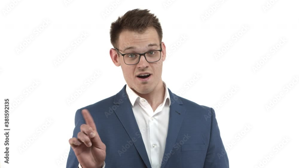 Handsome young blond businessman in blue suit and glasses, shaking head and finger, disapprove and forbid something, standing over white background Handsome young blond businessman in blue suit and glasses, shaking head and finger, disapprove and forbid something, standing over white background