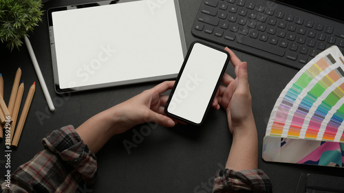 Female working mock up smartphone on worktable with mock up tablet