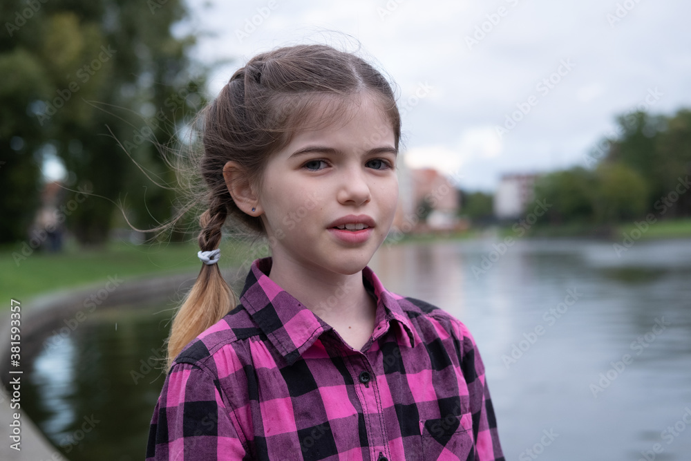 portrait of a little/ young girl in a plaid shirt by the lake