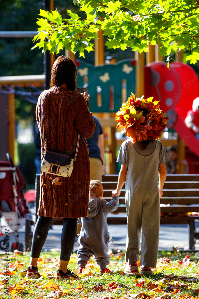 Little girl with a wreath of maple leaves standing next to her mother